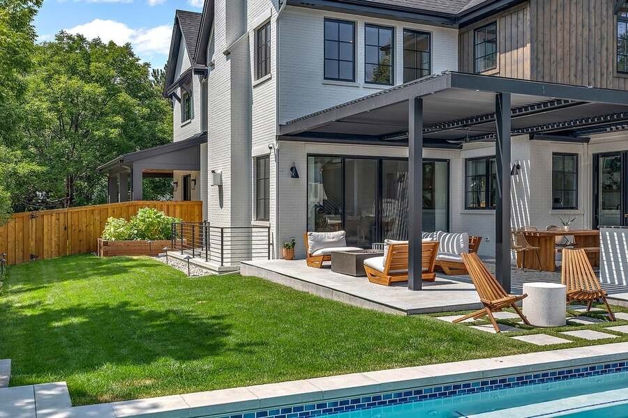 A beautiful alfresco space with a pool and fancy outdoor lounges.