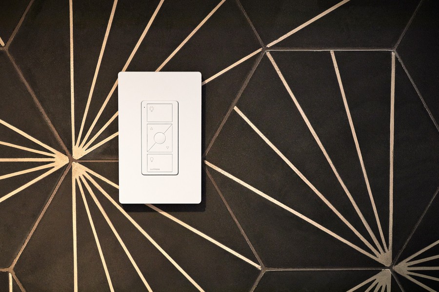 Close up of a Lutron smart lighting control switch mounted on a tiled wall.