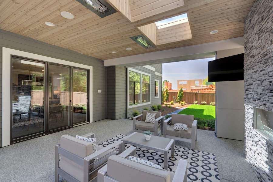 A covered patio with four plush chairs and a mounted outdoor TV in the corner. 